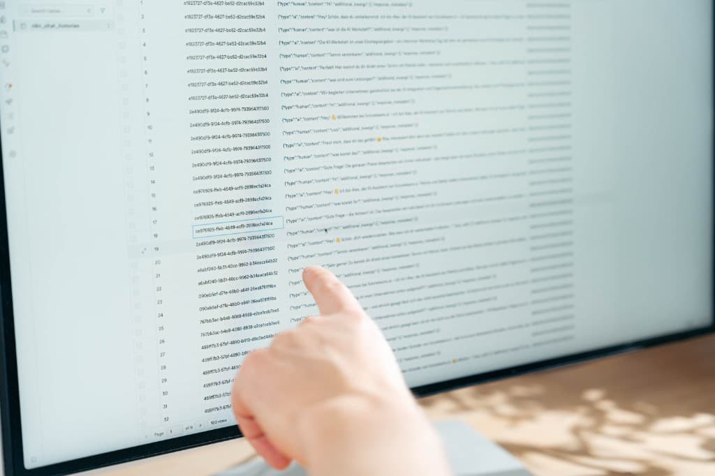 Person zeigt auf Chat-Verläufe eines KI-Interviews in einer Datenbank-Ansicht